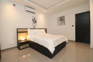 - une chambre avec un grand lit et une table de nuit dans l'établissement VOAK Home, à Douala