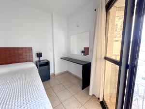 a bedroom with a bed and a desk and a window at Apartamento no Mercure - canal 3 in Santos