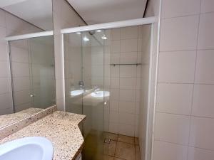 a bathroom with a sink and a glass shower at Apartamento no Mercure - canal 3 in Santos