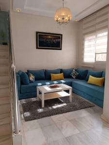 - un salon avec un canapé bleu et une table basse dans l'établissement Villa près de l’aéroport casa, à Deroua