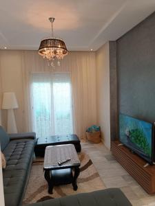 een woonkamer met een bank en een flatscreen-tv bij Villa près de l’aéroport casa in Deroua