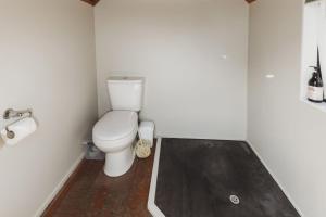 a bathroom with a toilet and a wooden floor at The River Retreat Off The Grid in Inglewood