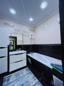 baño con bañera grande y espejo grande en Апартаменты 2 ком в ЖК Альтаир возле гипер Дина, en Aktobe