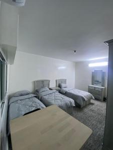um quarto com três camas e uma mesa em شقه مفروشه مميزه em Irbid