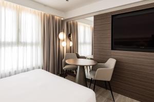 um quarto de hotel com uma cama e uma mesa e uma televisão em AC Hotel by Marriott St Julian's em St. Julian's
