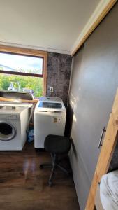Habitación pequeña con silla, lavadora y secadora. en Hostal Turismo El Campesino, en Puerto Natales