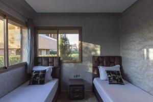 due letti in una stanza con due finestre di Prestigia golf city porte agate a Marrakech