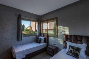 una camera da letto con due letti e una finestra di Prestigia golf city porte agate a Marrakech