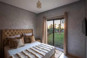 una camera da letto con un letto e una porta scorrevole in vetro di Prestigia golf city porte agate a Marrakech Altre 8 foto