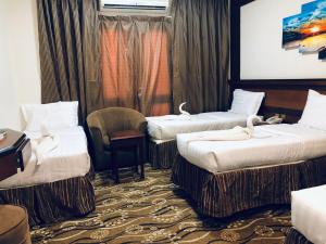 une chambre d'hôtel avec trois lits et une chaise dans l'établissement فندق الزائر الأخيار الفندقية, à La Mecque 8 autres photos
