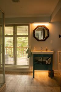 La salle de bains est pourvue d'un lavabo et d'un miroir. dans l'établissement Birdsong Cottage, à Paraparaumu