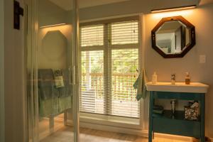 a bathroom with a sink and a mirror at Birdsong Cottage in Paraparaumu