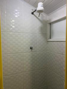 a white tiled shower with a light and a window at SOL in Búzios
