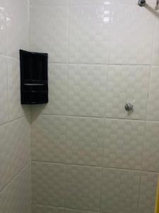 una ducha de azulejos blancos con dispensador de jabón negro en SOL, en Búzios