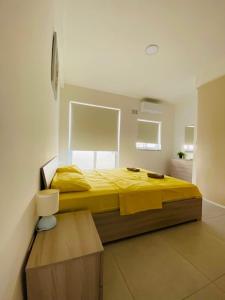 sypialnia z dużym łóżkiem z żółtą pościelą w obiekcie Sunquest court w mieście St Paul's Bay