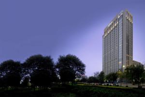 un edificio alto con árboles delante de él en Hilton Xi'an High-tech Zone en Xi'an