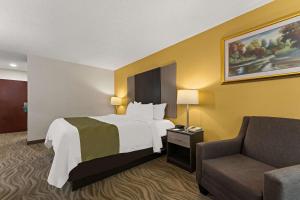 Habitación de hotel con cama y silla en Quality Inn Sandersville, en Sandersville