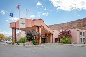 een roze gebouw met twee vlaggen ervoor bij Quality Suites Moab near Arches National Park in Moab