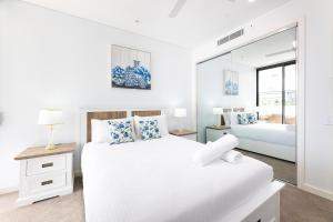 a white bedroom with two beds and a mirror at Solaris 310 in Forster +19 photos