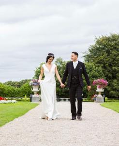 a bride and groom holding hands while walking down a path at Radisson Blu St. Helen's Hotel in Stillorgan