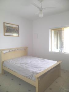 ein Bett in einem weißen Zimmer mit einem Fenster in der Unterkunft Peruíbe - Oasis - Casa espaçosa, lugar tranquilo in Peruíbe + 14 Fotos