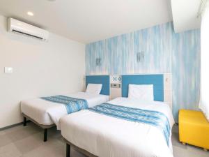 two beds in a room with blue and white walls at Comfort Hotel Ishigaki Island in Ishigaki Island