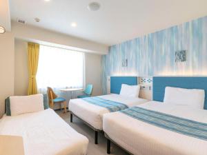 a hotel room with two beds and a table at Comfort Hotel Ishigaki Island in Ishigaki Island