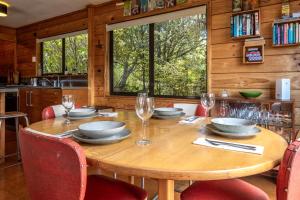 a wooden table with plates and glasses on it at Onetangi Bliss - Waiheke Island Holiday Home in Onetangi +21 photos