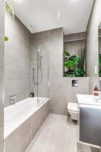 uma casa de banho com uma banheira, um WC e um lavatório. em Modern 2BR 2BA with Free Parking - Sleeps 6 em Hemel Hempstead