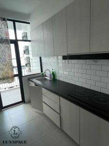 a kitchen with white cabinets and a sink and a window at Kuching City 3rd Mile Batu Kawa Cozy Apartment in Kuching +8 photos