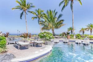 a swimming pool with palm trees and a beach at Hali'i Kai - Waikoloa in Waikoloa