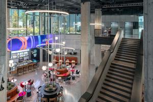 a lobby with a staircase and tables and chairs at STAGES HOTEL Prague, a Tribute Portfolio Hotel in Prague