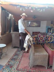 un hombre con sombrero parado en una sala de estar con un perro en Café Autor Dan et Eger Nouvelle Restaurant en Ouzoud