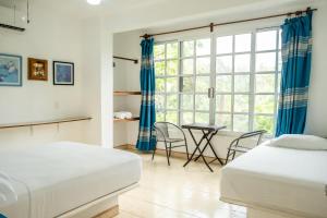 a bedroom with two beds and a table and a window at Casa Mazunte Tierra Viva in Mazunte