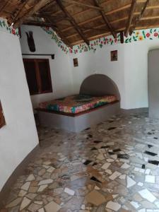 een slaapkamer met een bed en een stenen vloer bij Campement Nyabinghi in Abémé