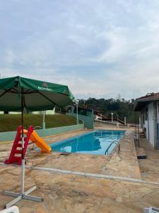 een zwembad met een parasol en een glijbaan bij Villagio Aguas do Jaguari Pousada in Santa Isabel