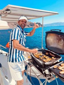 un hombre cocinando comida en una parrilla en un barco en RM Holiday Home, en Hikkaduwa