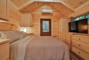 a bedroom in a log cabin with a bed and a tv at Stefan Cabin Nature-nested Tiny Home Hot Tub in Chattanooga