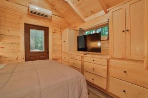 a bedroom with a bed and a flat screen tv at Stefan Cabin Nature-nested Tiny Home Hot Tub in Chattanooga