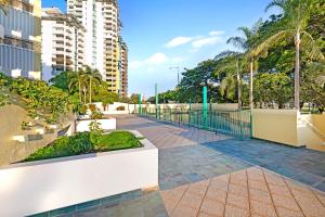 a walkway with a fence and palm trees at Harbour Haven - A Parkside CBD Address in Larrakeyah