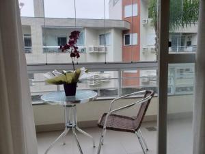 une table et une chaise devant une fenêtre dans l'établissement Apartamento na Praia Brava - Florianópolis, à Florianópolis