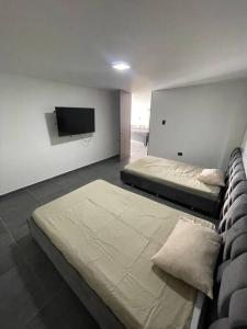um quarto com 2 camas e uma televisão de ecrã plano em Casa combia de lujo em Pereira