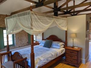 um quarto com uma cama de dossel e piso em madeira em Morialta Barns em Norton Summit