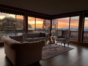 uma sala de estar com sofás e cadeiras e um pôr-do-sol em Cozy and nice stay with sunset view! em Mooroolbark