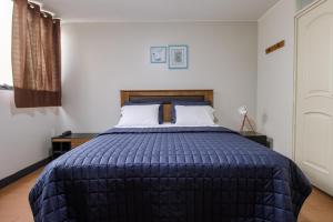 a bedroom with a large bed with a blue comforter at San Miguel Awanka Hotel in Lima