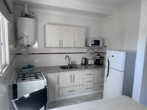 a kitchen with white cabinets and a white refrigerator at Apart Luro I in Santa Rosa +8 photos