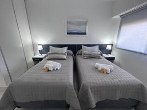 two beds in a bedroom with two teddy bears on them at Apart Luro I in Santa Rosa