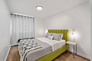 Schlafzimmer mit einem grünen und weißen Bett und einem Tisch in der Unterkunft Spacious 2BR Top Floor with Balcony Free WiFi in Fort McMurray