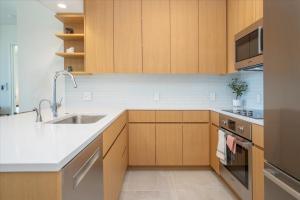 Una cocina con gabinetes de madera y un fregadero. en Sky Ala Moana 2908 condo, en Honolulu