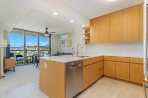 a kitchen with wooden cabinets and a dining room at Sky Ala Moana 2908 condo in Honolulu